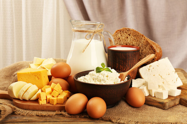 Tasty dairy products with bread on table on fabric background