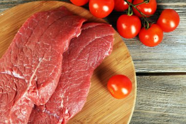 Kesme tahtası ahşap arka plan üzerinde kiraz domates ile ham sığır eti biftek