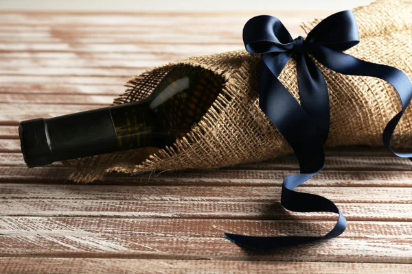 ワインのボトルに包まれた木の板の背景に黄麻布 — ストック写真
