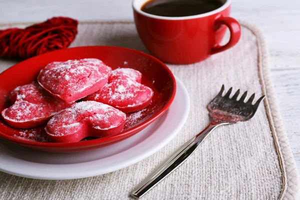 Cookies in form of heart on plate with cup of coffee on napkin and color wooden planks background — Stock Photo, Image