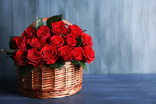 Boeket van rode rozen in mand op houten achtergrond — Stockfoto