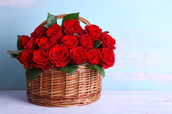 Bouquet of red roses in basket on wooden background — Stock Photo, Image