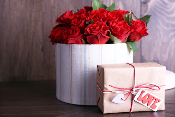 Bouquet of red roses in textile box with present on wooden background — Stock Photo, Image