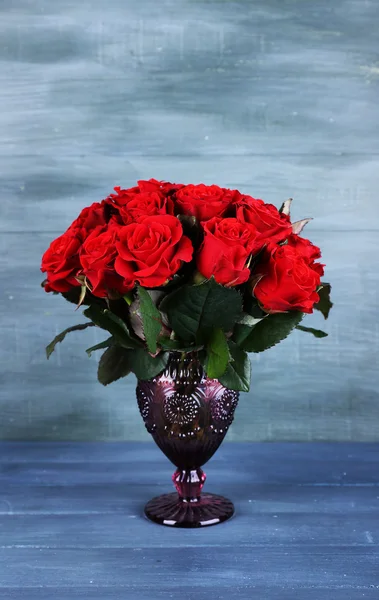 Bouquet of red roses in glass vase on wooden background — Stock Photo, Image