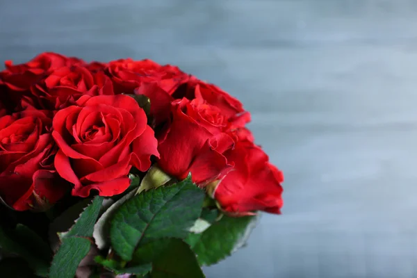 Boeket van rode rozen in glazen vaas op houten achtergrond — Stockfoto