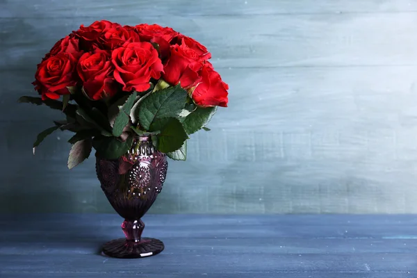Bouquet de roses rouges dans un vase en verre sur fond de bois — Photo