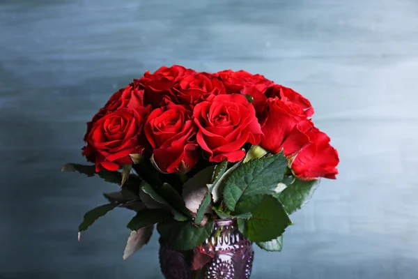 Ramo de rosas rojas en jarrón de vidrio sobre fondo de madera —  Fotos de Stock