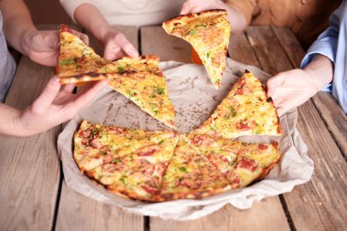 Dilim pizza alarak arkadaşlar eller