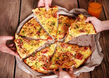 Dilim pizza alarak arkadaşlar eller