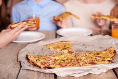 Dilim pizza alarak arkadaşlar eller