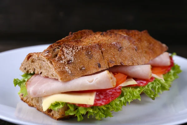 Frisches und schmackhaftes Sandwich mit Käse und Gemüse auf Teller auf Holzgrund — Stockfoto