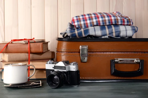 Vintage suitcase with clothes and books on wooden background — Stock Photo, Image