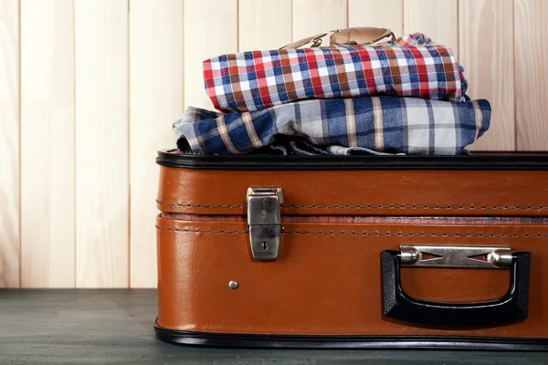 Vintage suitcase with clothes on wooden background — Stock Photo, Image