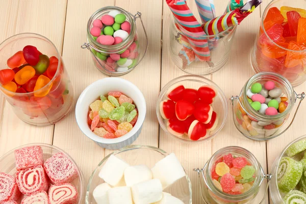 Sweetness in different containers on wooden background — Stock Photo, Image