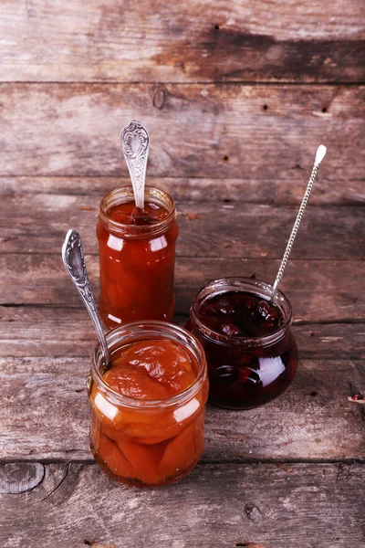 Jars of tasty jam on wooden background — Stock Photo, Image