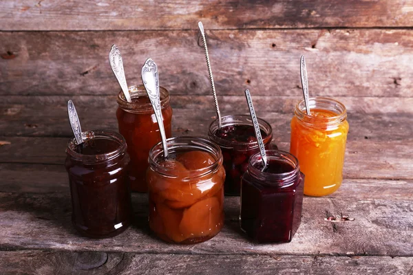 Jars of tasty jam on wooden background