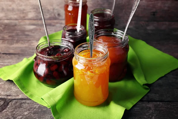 Gläser leckere Marmelade mit Serviette auf Holzgrund — Stockfoto