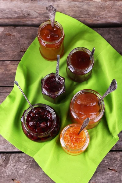 Gläser leckere Marmelade mit Serviette auf Holzgrund — Stockfoto