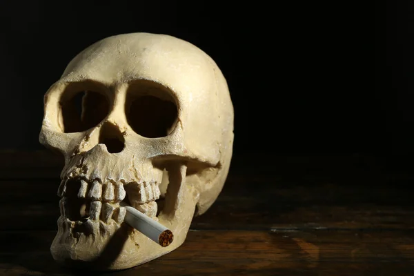 Κάπνισμα ανθρώπινο κρανίο με το τσιγάρο στο στόμα του σε σκούρο φόντο — Φωτογραφία Αρχείου