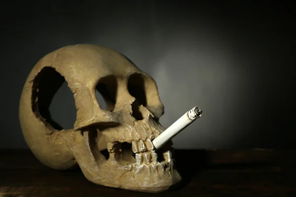 Κάπνισμα ανθρώπινο κρανίο με το τσιγάρο στο στόμα του σε σκούρο φόντο — Φωτογραφία Αρχείου