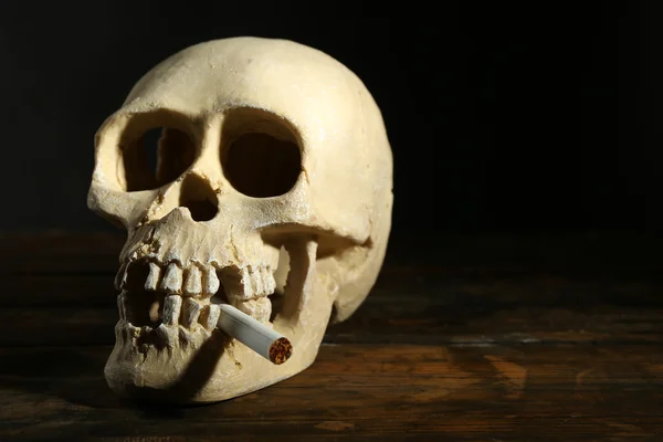 Menschenschädel rauchend mit Zigarette im Mund auf dunklem Hintergrund — Stockfoto