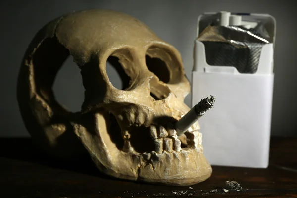 ヒューマン スカル暗い背景に彼の口のタバコの喫煙 — ストック写真