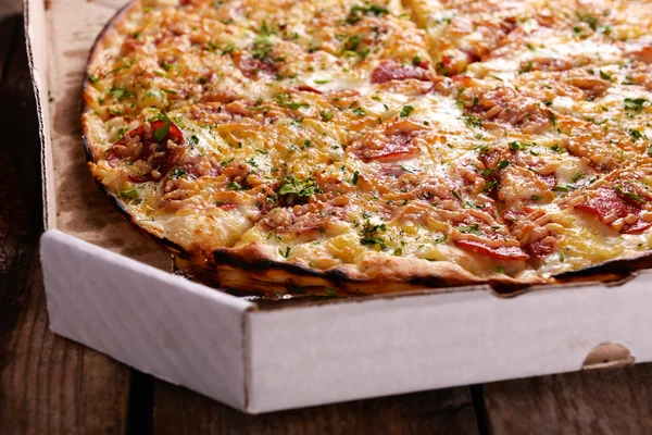 Tasty pizza in box on wooden background — Stock Photo, Image