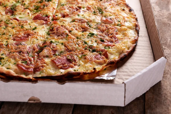 Tasty pizza in box on wooden background — Stock Photo, Image