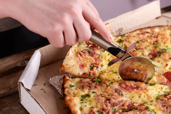 Girl cut pizza on table close up — Stock Photo, Image