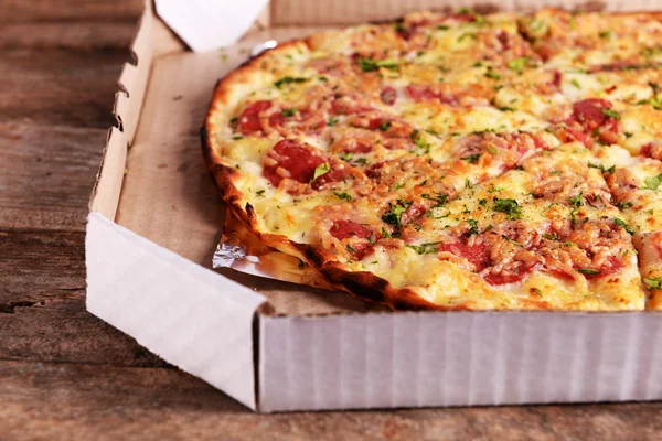 Tasty pizza in box on wooden background — Stock Photo, Image