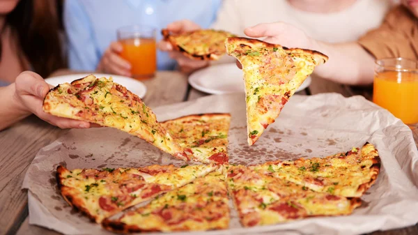 Le mani di amici che prendono fette di pizza — Foto Stock