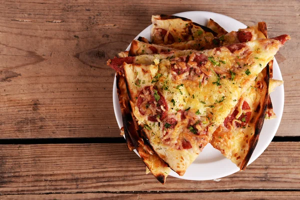 Sabrosas rebanadas de pizza en el plato en la mesa de madera —  Fotos de Stock