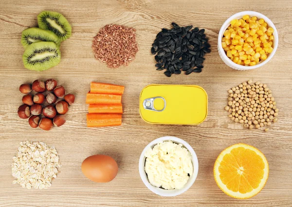 Různé potravinářské výrobky obsahující vitamíny na dřevěné pozadí — Stock fotografie