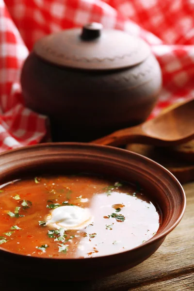 Ukrainian beetroot soup - borscht in bowl and pot, on napkin, on wooden background — Stock Photo, Image