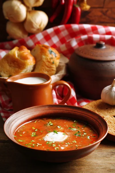 Oekraïense rode biet soep - Borsjt in kom en pot, op servet, op houten achtergrond — Stockfoto