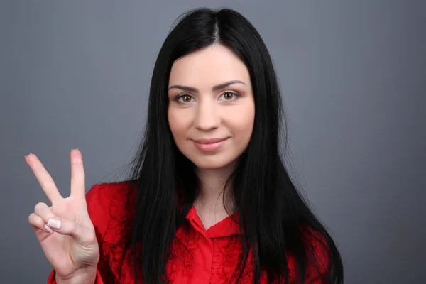 Portrait of young woman on grey background — Stock Photo, Image