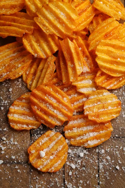 Heerlijke potato chips met zout op houten tafel close-up — Stockfoto