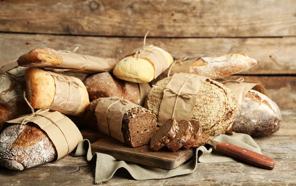 Verschillende vers brood, op oude houten tafel — Stockfoto