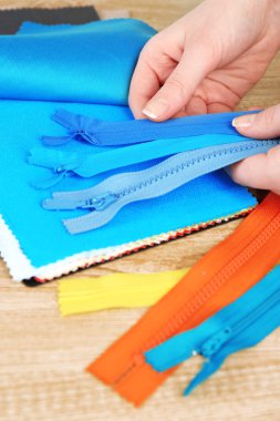 Renkli kumaş örnekleri ve ahşap masa arka plan üzerinde eller içinde fermuar