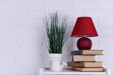 Lamba, bitki, seramik sulama pot ve masa üstü beyaz tuğla duvar arka plan üzerinde kitap ile iç tasarım