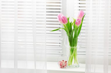 Pencere arka plan üzerinde cam vazoda güzel pembe laleler