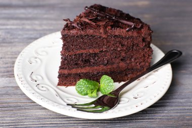 Ahşap masa arka plan, closeup nane ile beyaz tabak içinde lezzetli çikolatalı kek