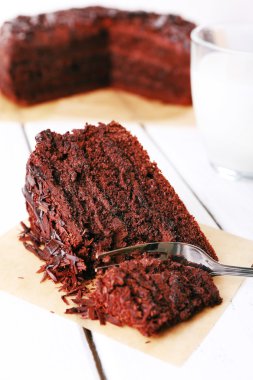 Bir yaprağına parşömen ve ahşap masa arka plan üzerinde süt lezzetli çikolatalı pasta dilimlenmiş