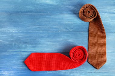 Colorful male ties on color wooden table background clipart