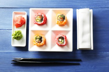 Plaka, soya sosu ve çubuk renk ahşap arka plan üzerinde suşi rulo