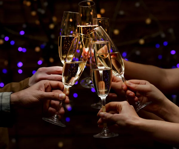 Clinking glasses of champagne in hands on bright lights background — Stock Photo, Image