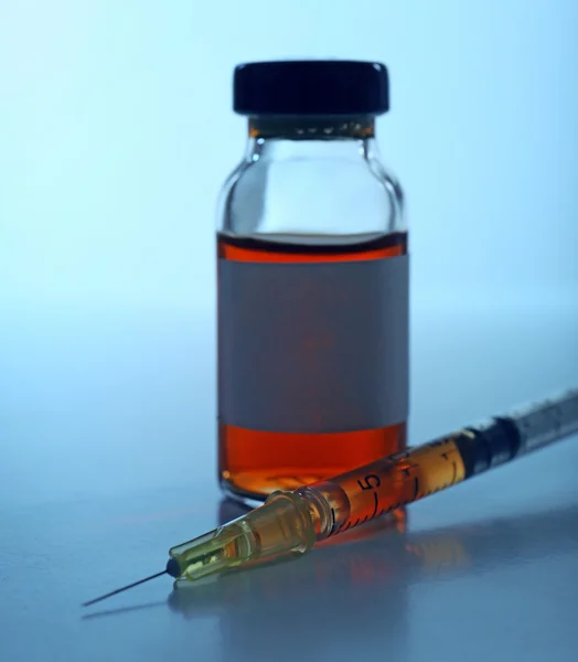 Medical ampule with syringe on blue background — Stock Photo, Image