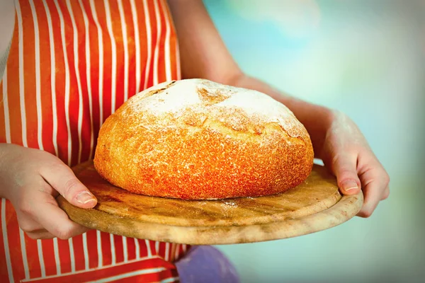 パンは新鮮な明るい背景をぼかした写真の木製まな板の上の女性の手でパンします。 — ストック写真