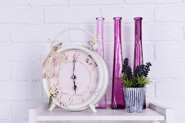 Diseño de interiores en la mesa con despertador, planta y jarrones decorativos sobre fondo de pared de ladrillo blanco —  Fotos de Stock