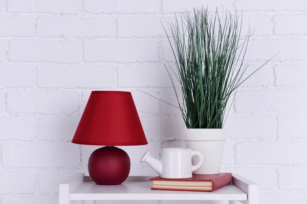 Diseño interior con lámpara, planta, maceta de cerámica y libro sobre mesa sobre fondo de pared de ladrillo blanco —  Fotos de Stock
